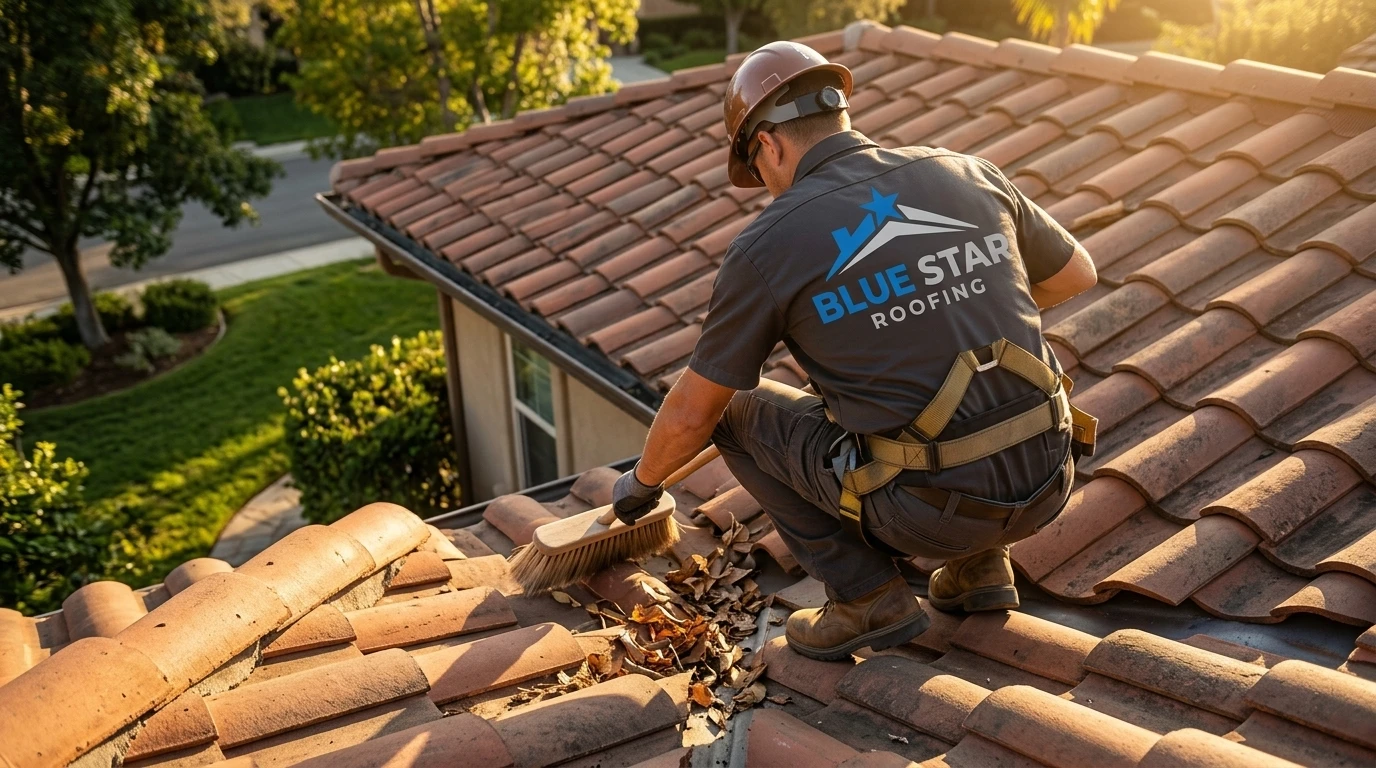 A roofing technician clearing debris from a roof valley as part of a roof maintenance Irvine seasonal inspection service